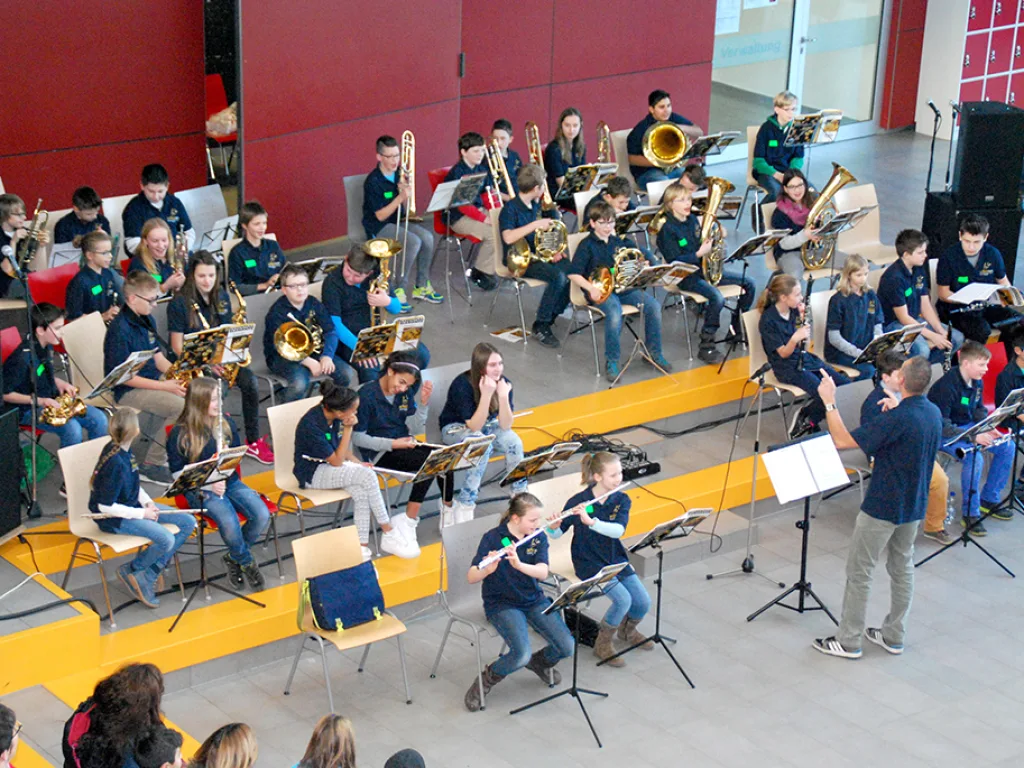 Das Blasorchester spielt in der Pausenhalle an Notenständern.